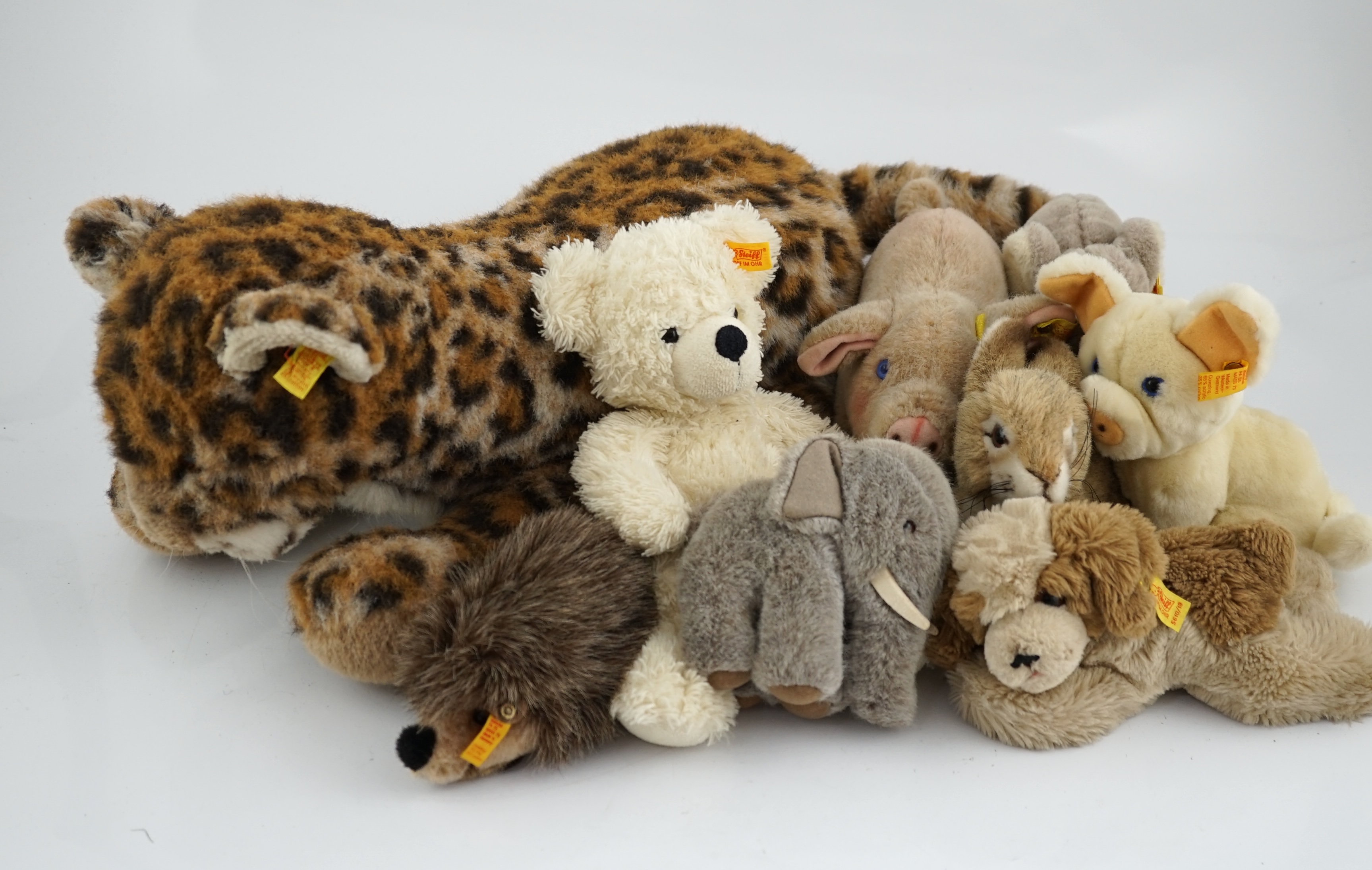 A large size Steiff yellow tag leopard, eight yellow tag animals, a Steiff button in the ear book and a book of Steiff postcards